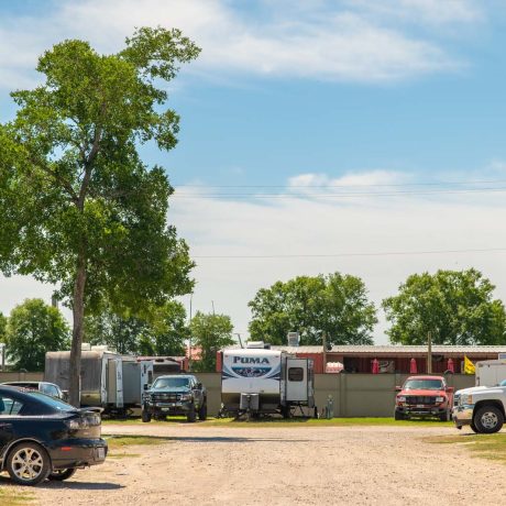 dirt road with cars and trailers parked in lots to the sides at Lost River RV